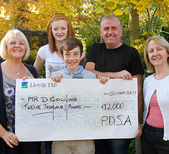 A family poses with their cheque after winning the PDSA Lottery