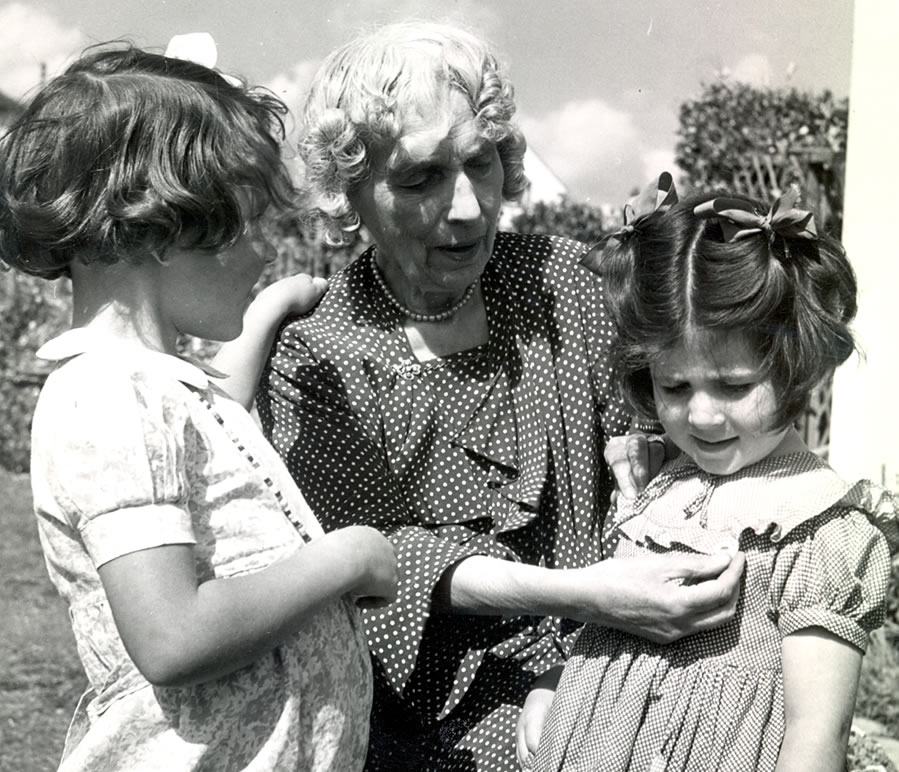 An elderly Maria Dickin pins a Busy Bee membership Badge to a young girl